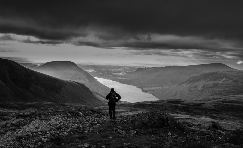 A walker on Scafell Pike looking over Wast Water.